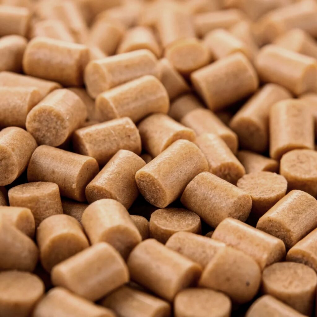 Gros plan sur des granulés de masterbatch matériau à bilan carbone négatif, un additif concentré à base de biomasse pour réduire l'empreinte carbone des plastiques.